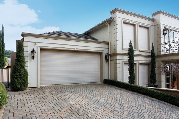 Modern beige house with a garage and paved driveway under a blue sky
