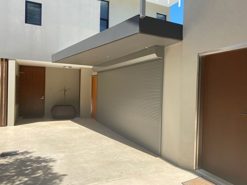 Modern building courtyard with beige walls, brown doors, and a large gray roll-up garage door