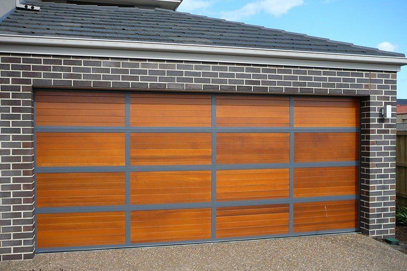 Orange wooden garage door set in a gray brick house facade