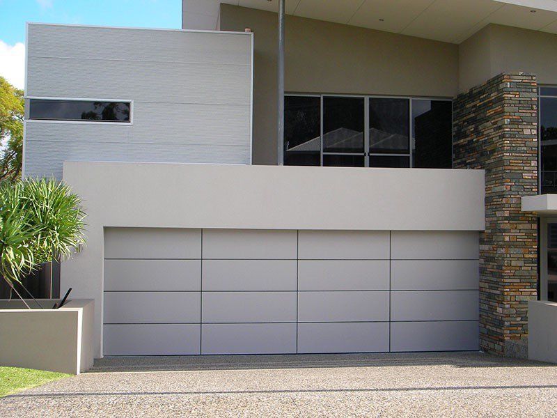 Modern house exterior with a gray garage door, white facade, and stone column.