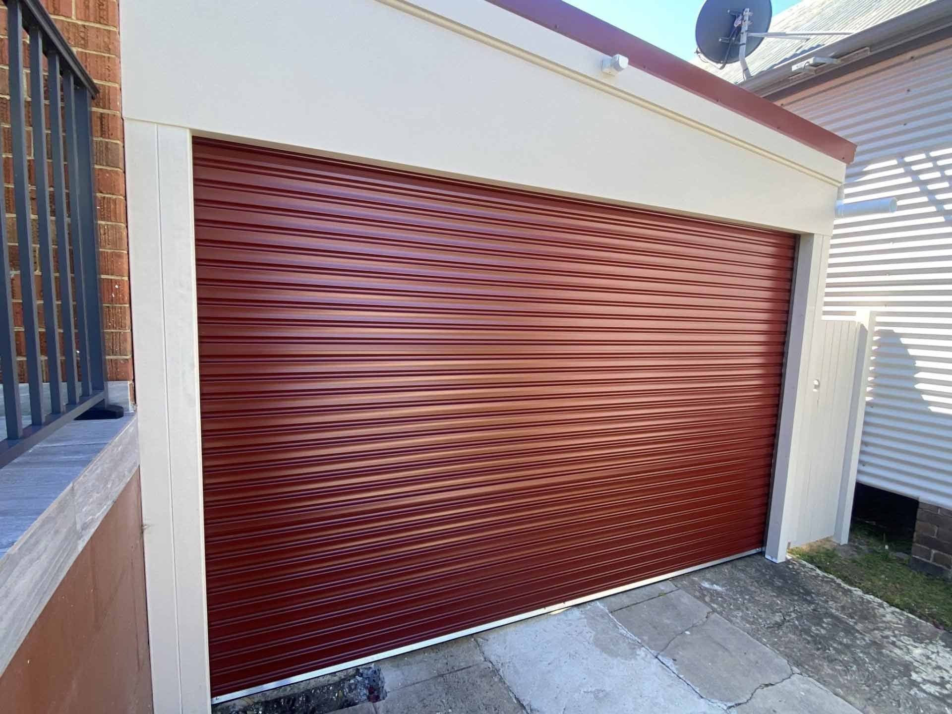 Red sectional garage door with woodgrain finish on a residential exterior.