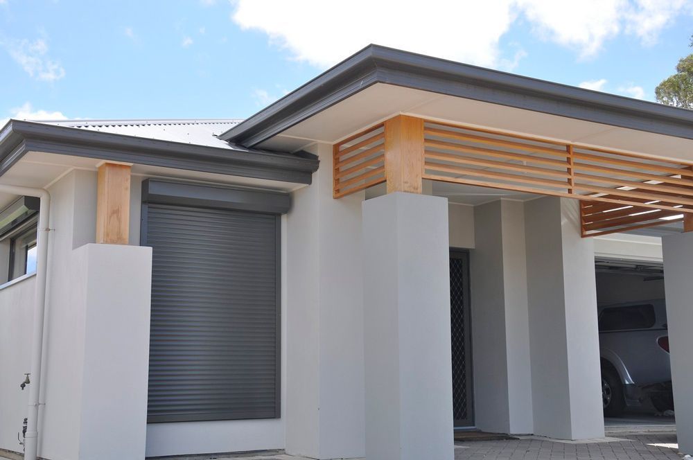 Modern white house exterior with gray garage door and wooden pergola over the entryway