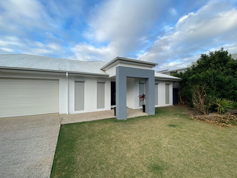 Modern house entrance with white siding, gray trim, and a small front lawn under a cloudy sky