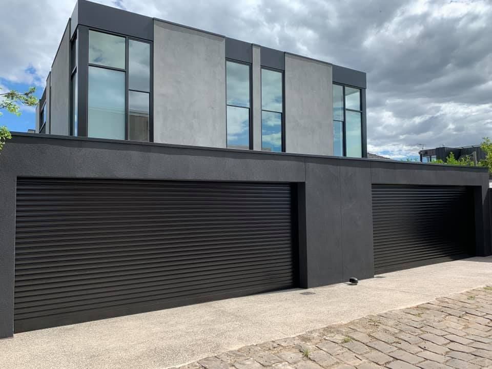Modern black-and-gray house with large windows and two black garage doors