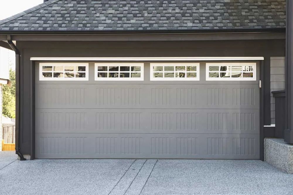 Gray two-car garage door with small windows on a house exterior