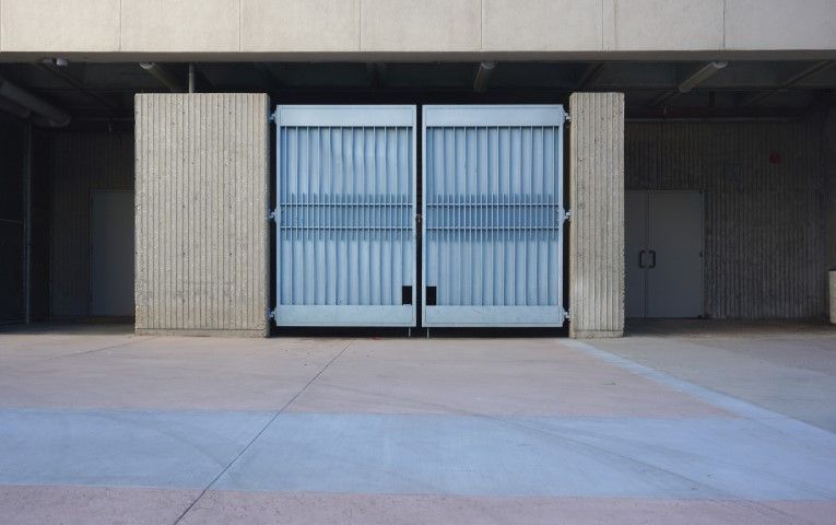 Dumpster area exposed behind open metal doors