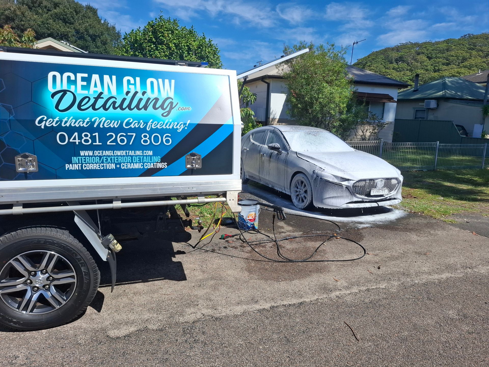 A car is sitting in front of a truck that says ocean glow detailing. – Ocean Glow Car Detailing in Long Jetty NSW