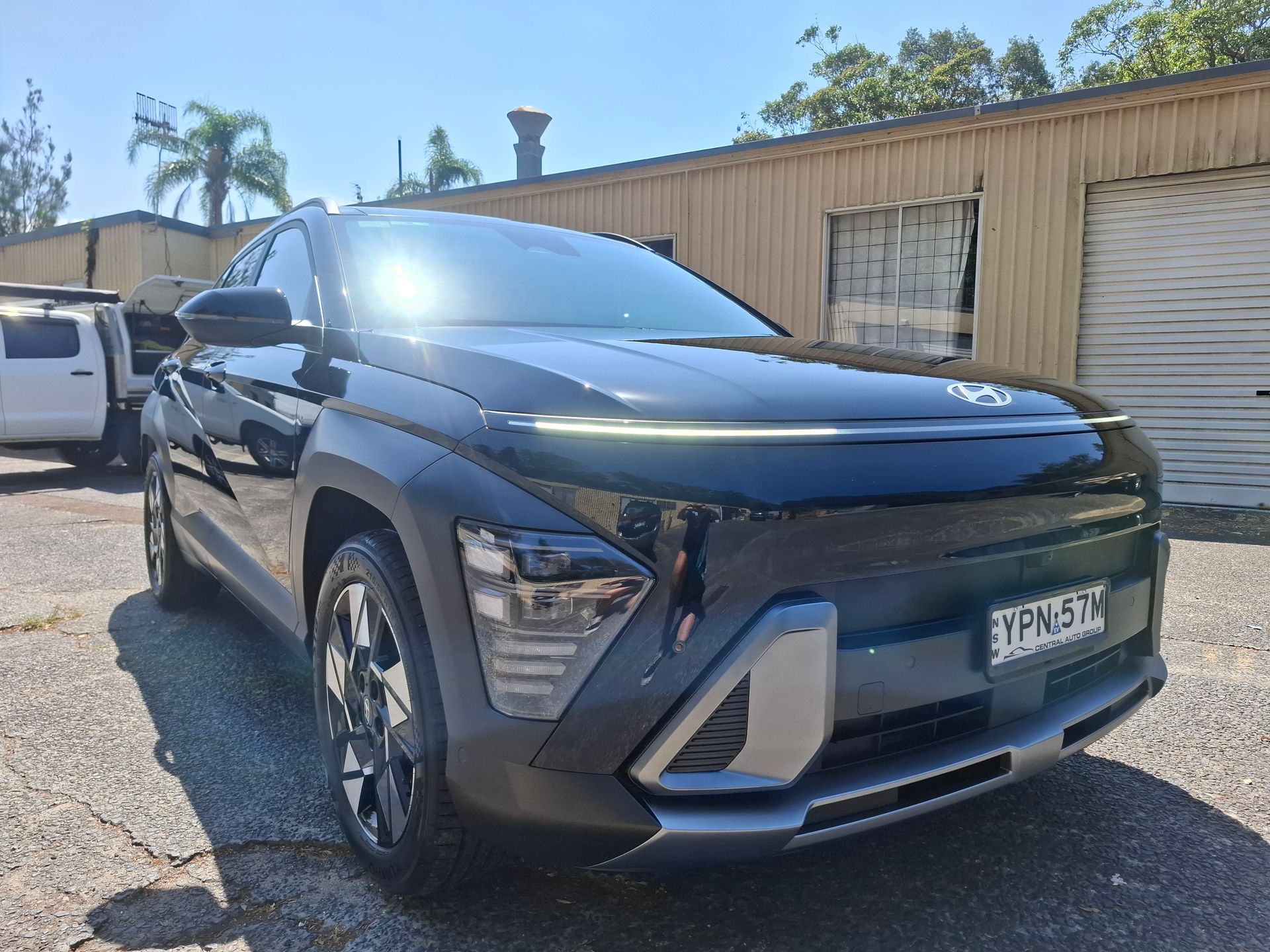 A black car is parked in a parking lot in front of a building. – Ocean Glow Car Detailing in Long Jetty NSW