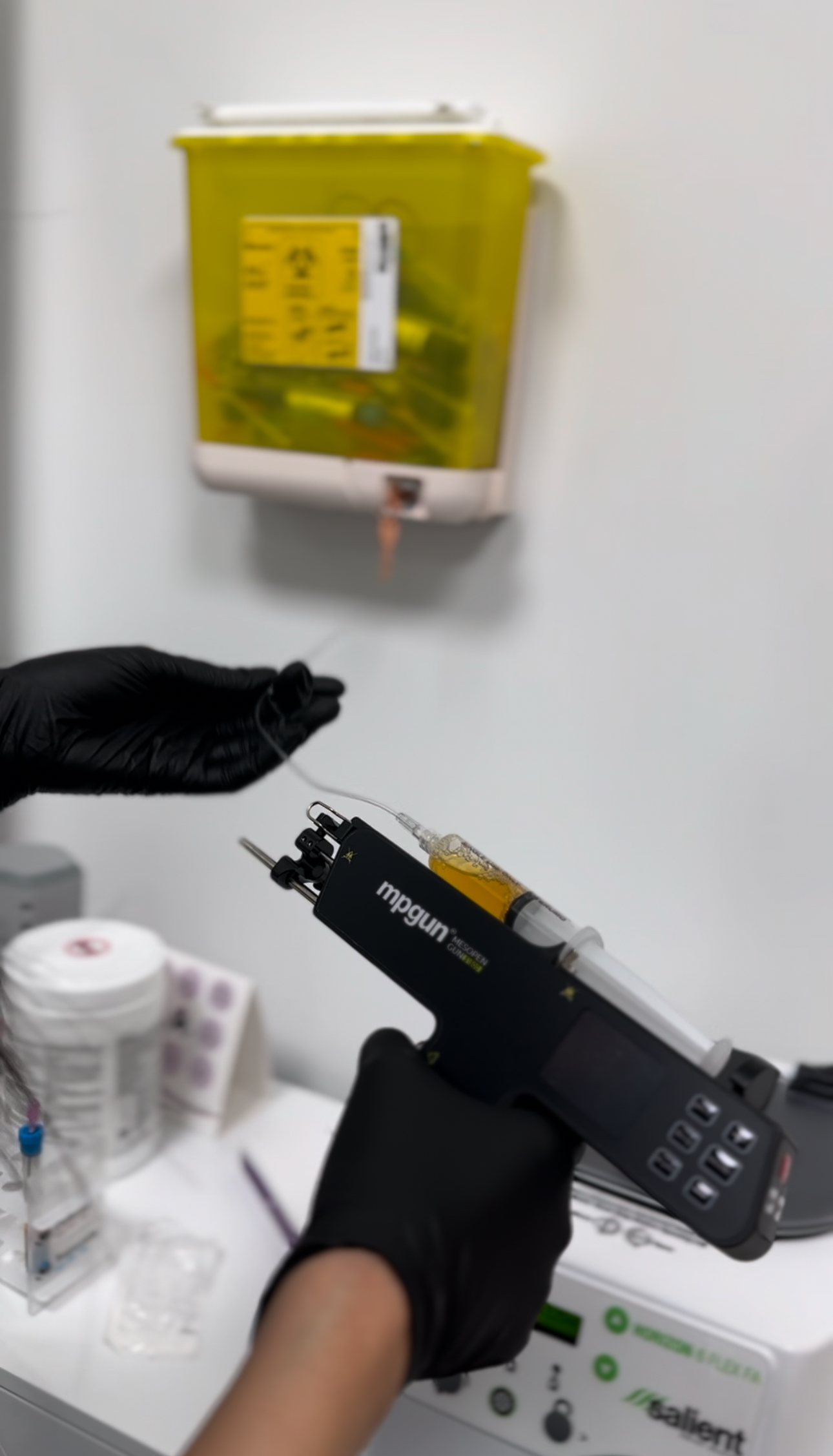 A person wearing black gloves is holding a syringe in their hand