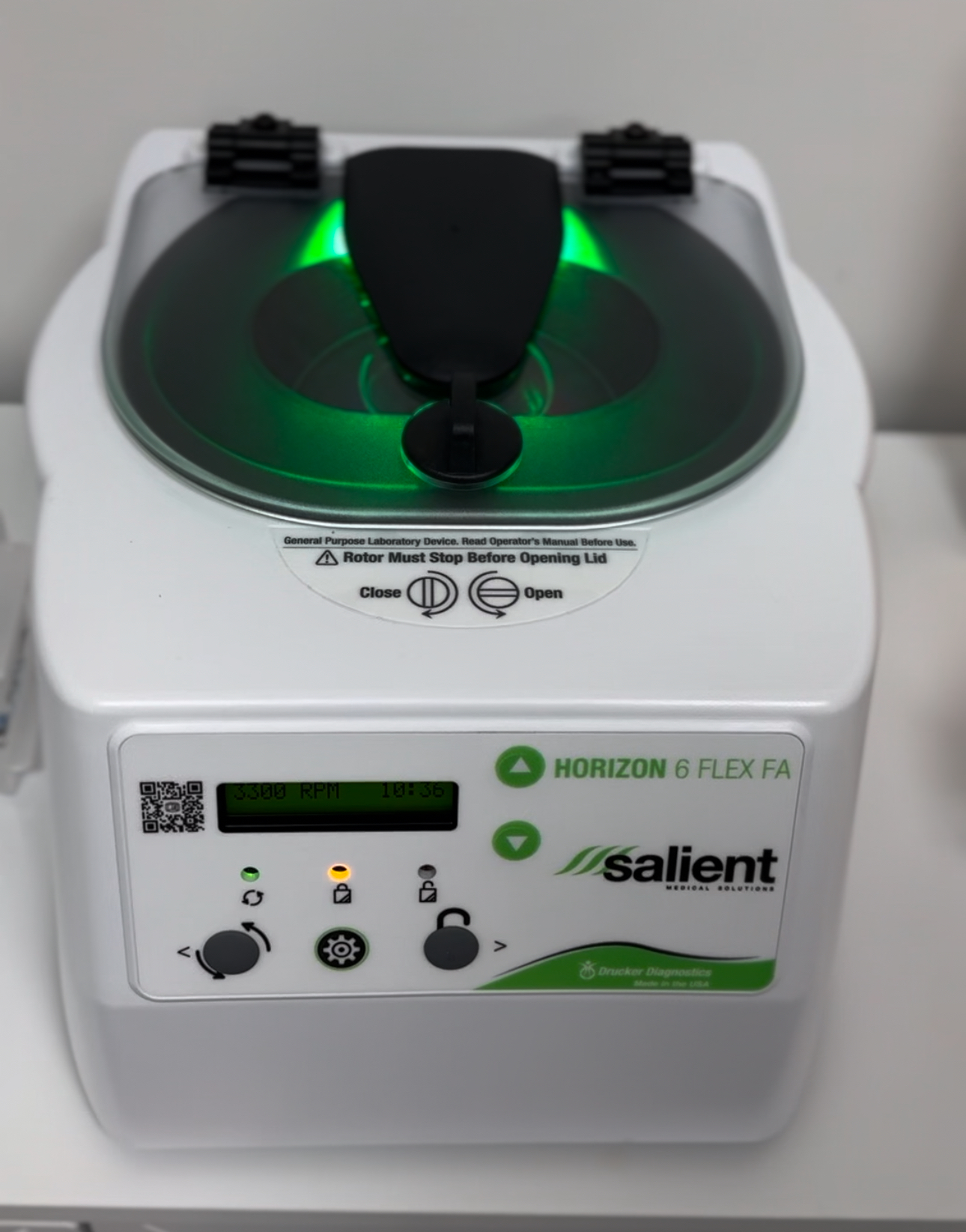 A white and green machine is sitting on a white table.