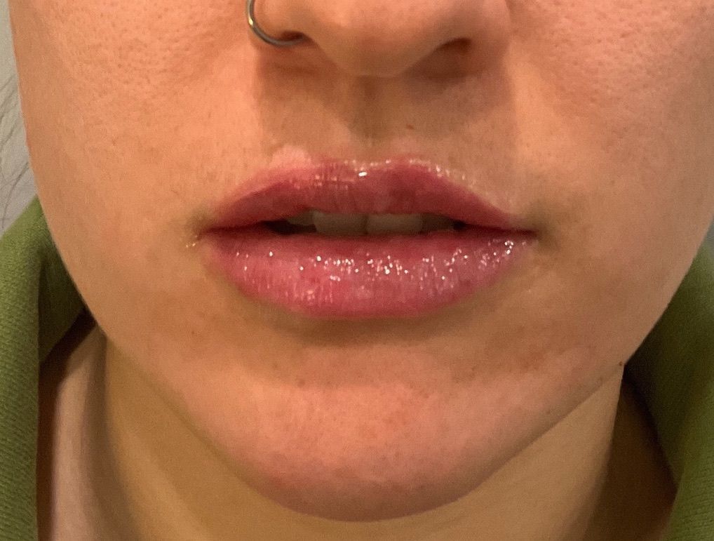 A close up of a woman 's lips with a nose ring.