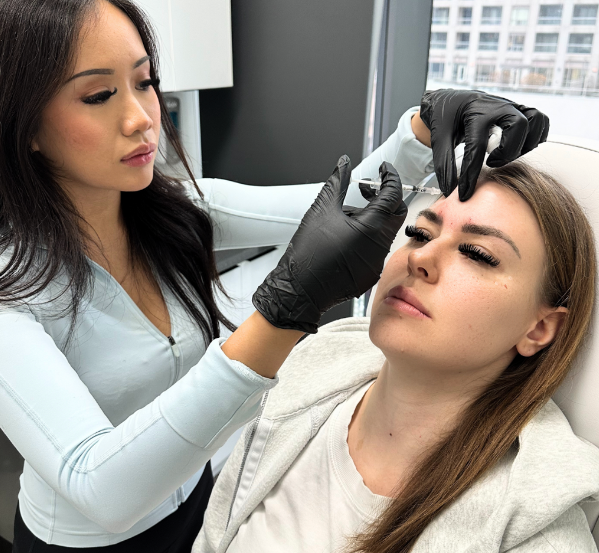 A woman is getting a botox injection in her forehead.