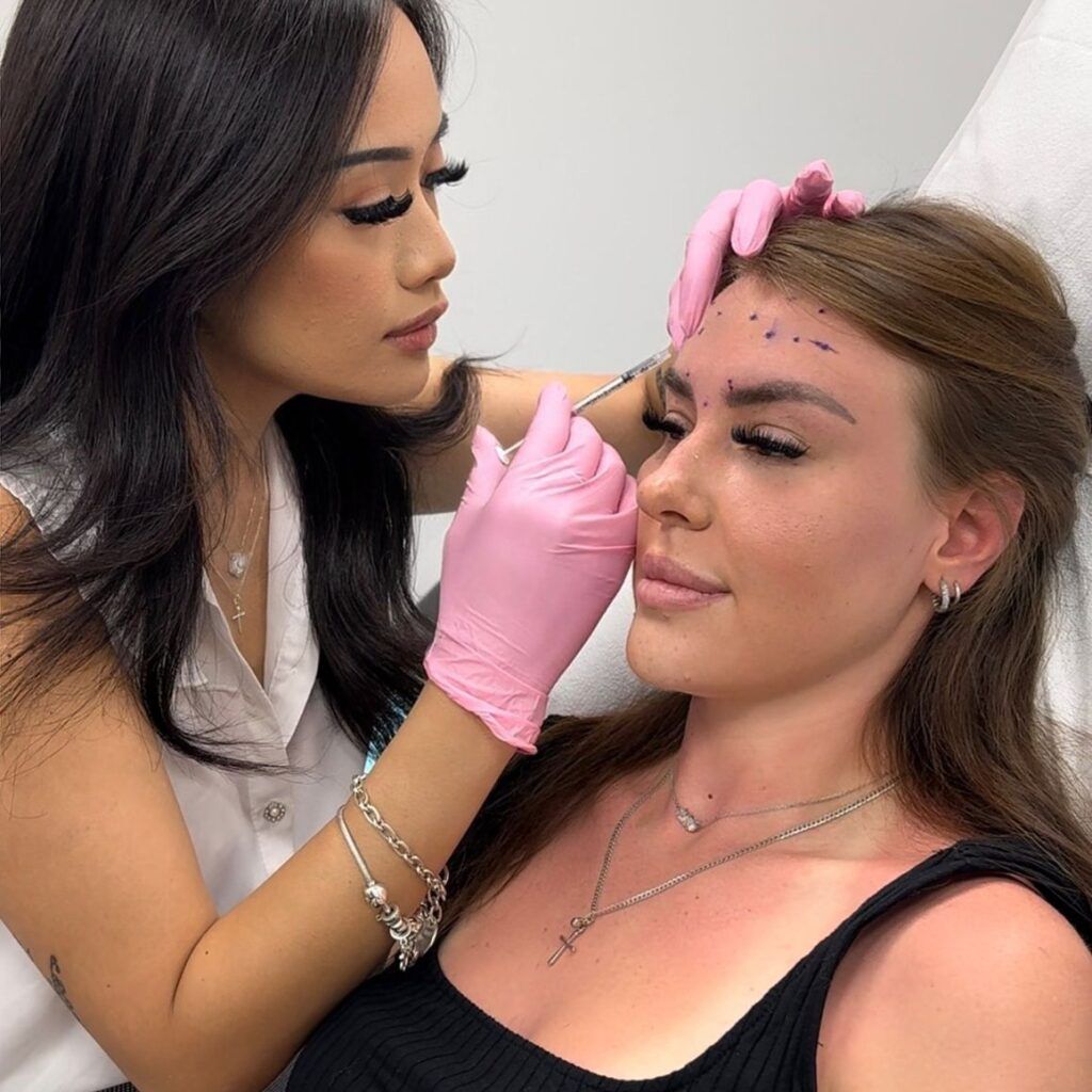 A woman is getting a botox injection in her forehead.