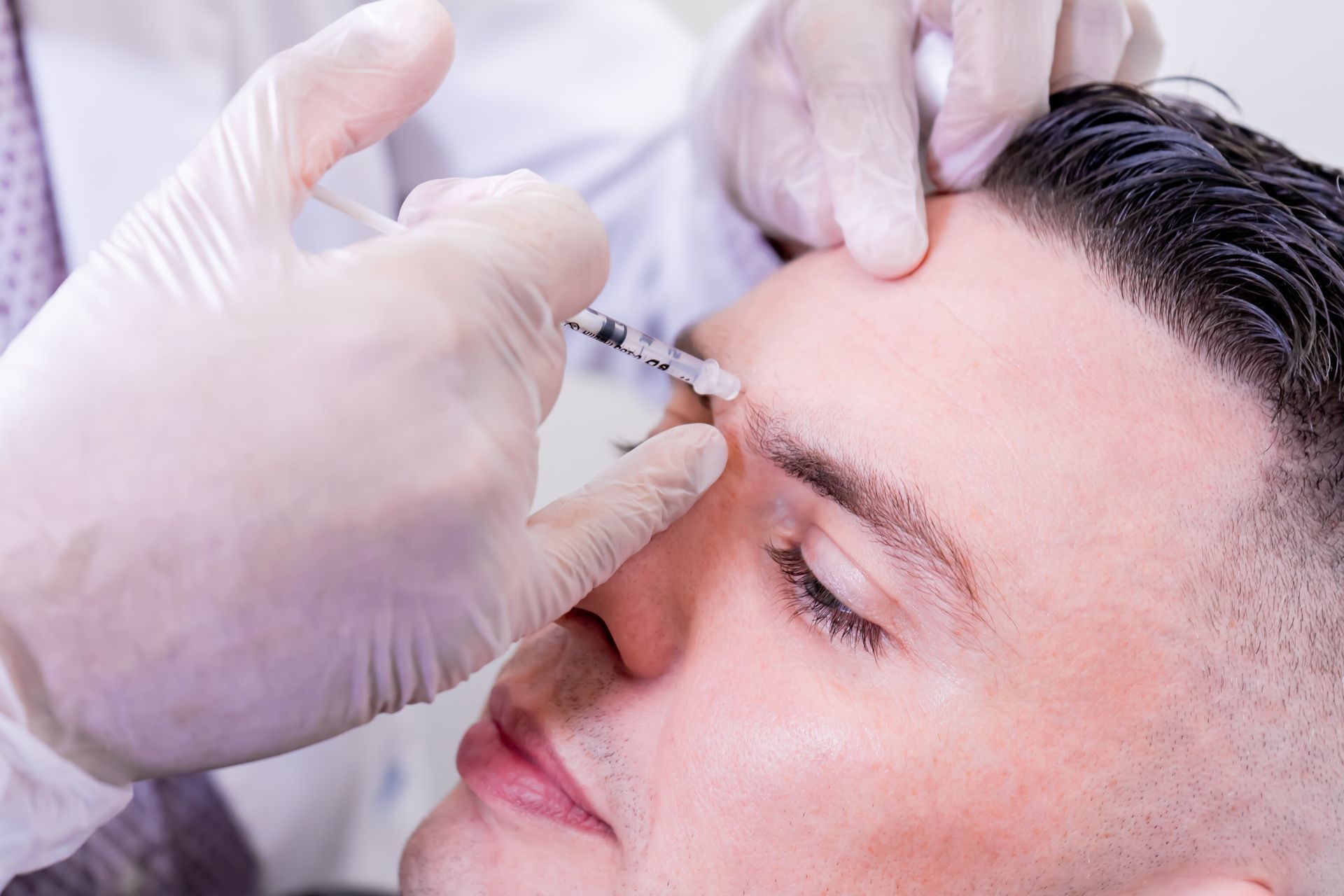 A man is getting a botox injection in his forehead.