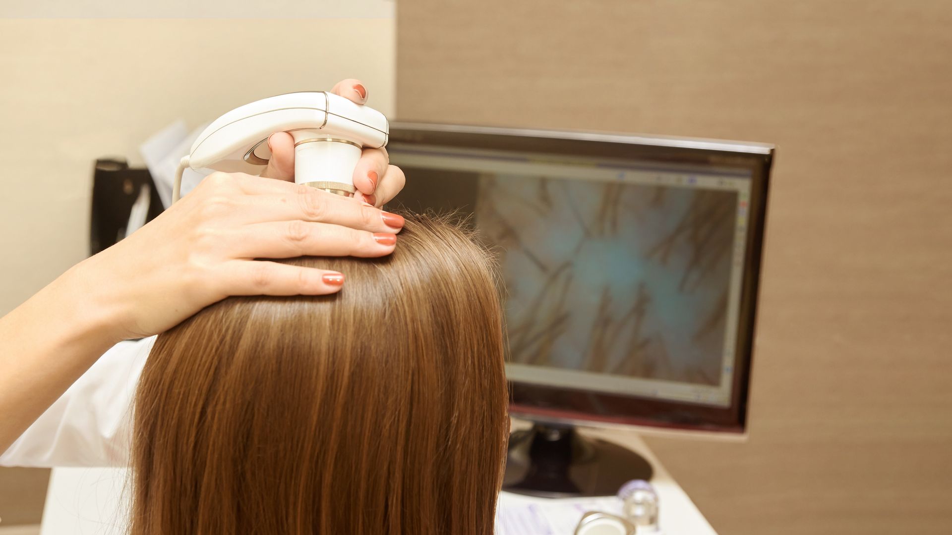 A woman is getting her hair examined by a doctor in front of a computer screen.