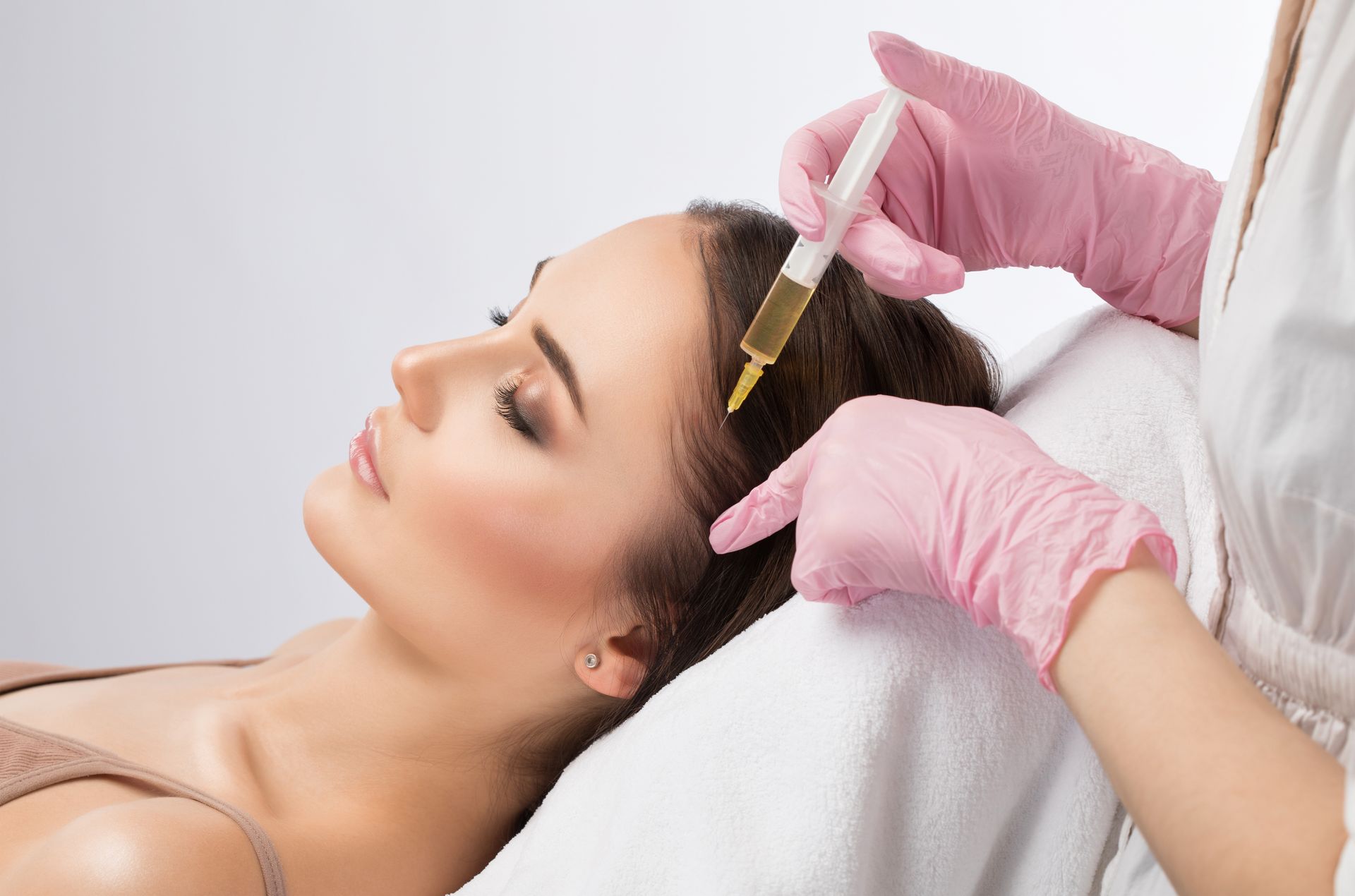 A woman is getting a botox injection in her head.