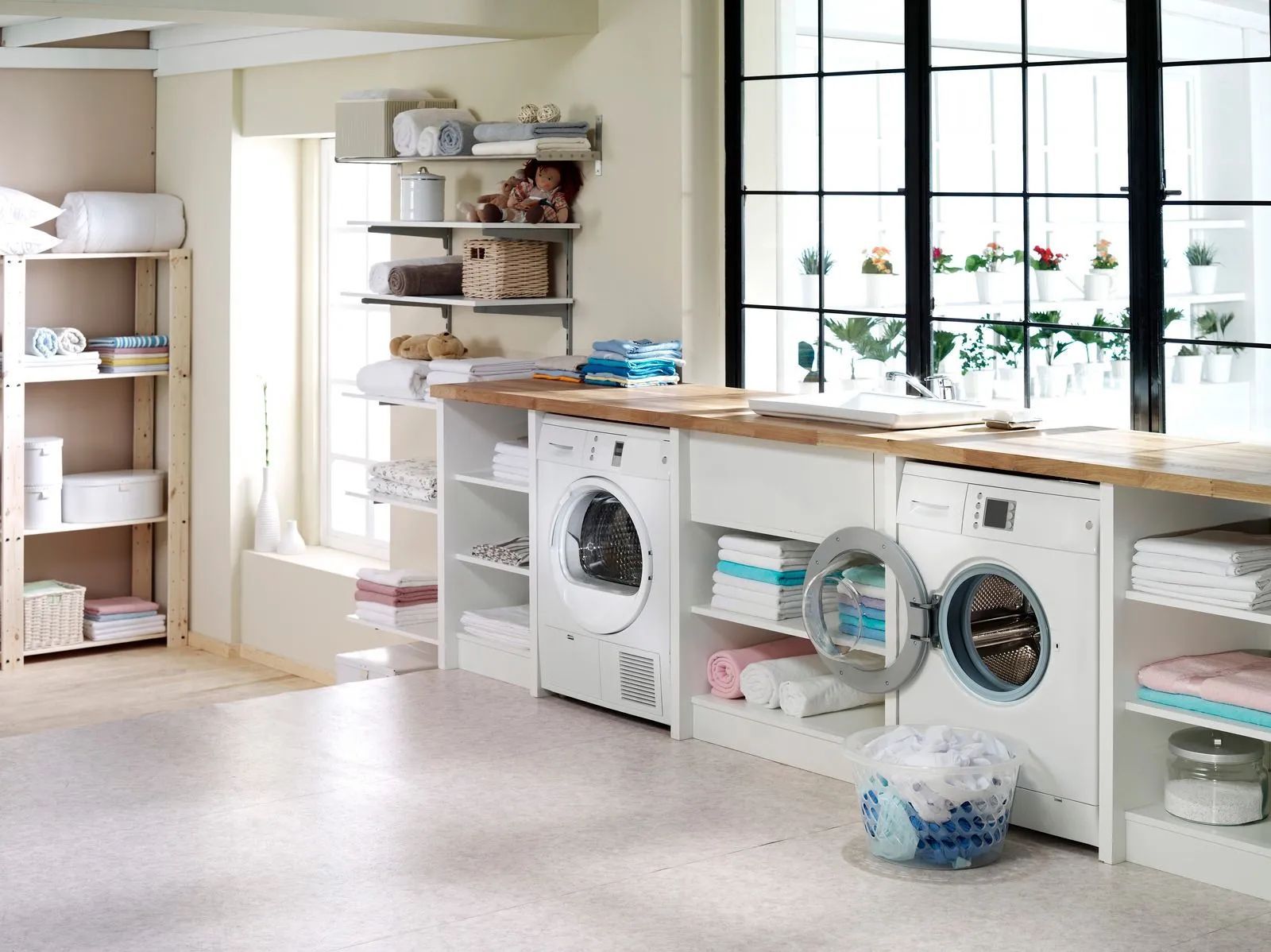 Laundry room with washer, dryer, shelves, and a large window with sunlight.