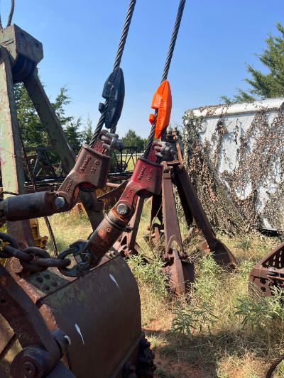 A bunch of old rusty machinery is sitting in a field with two Ropinator devices installed.