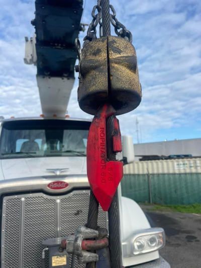 A crane hook is attached to the front of a white truck with a Ropinator pictured.