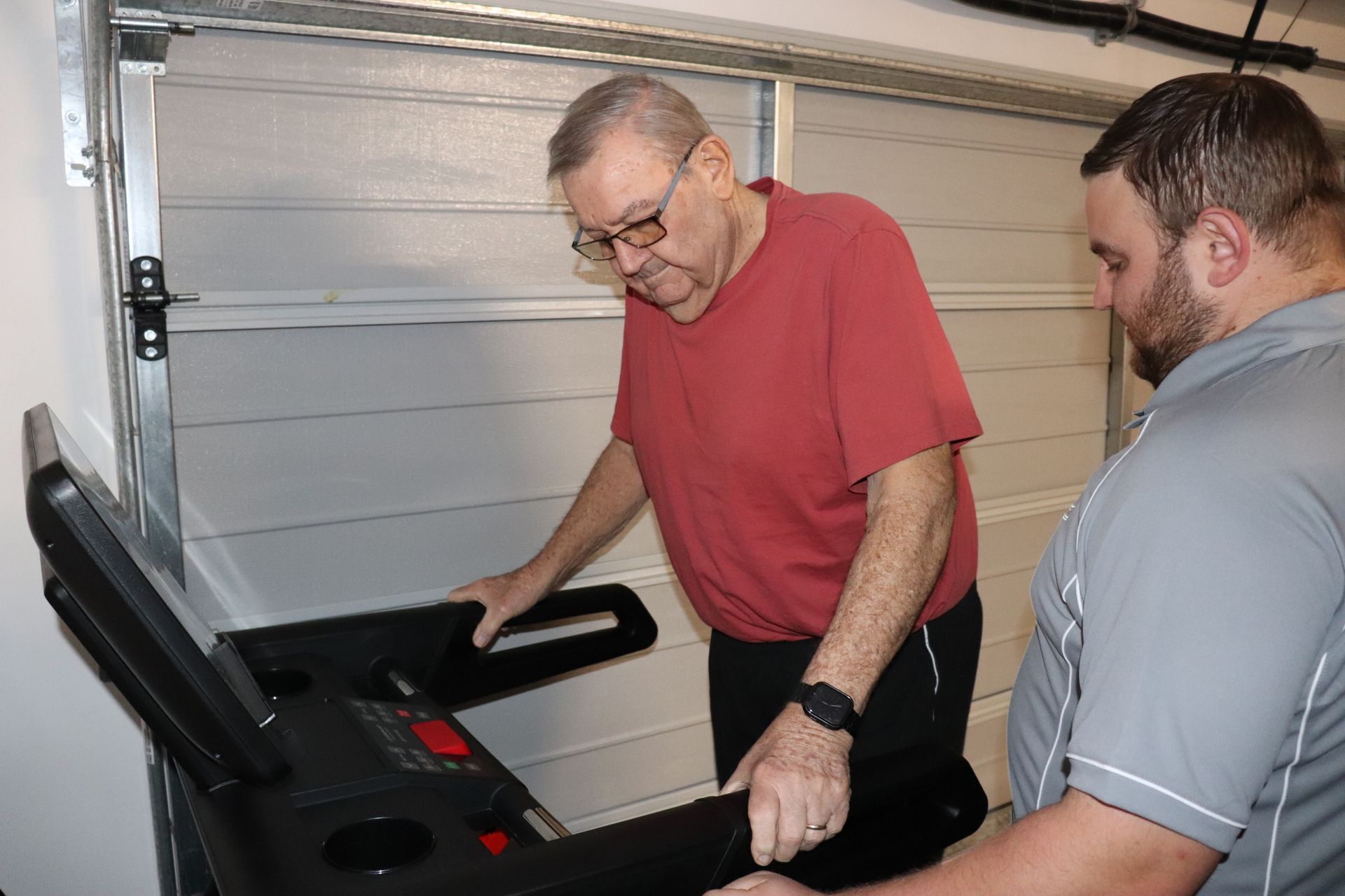 Older person walking on a treadmill with a personal trainer 