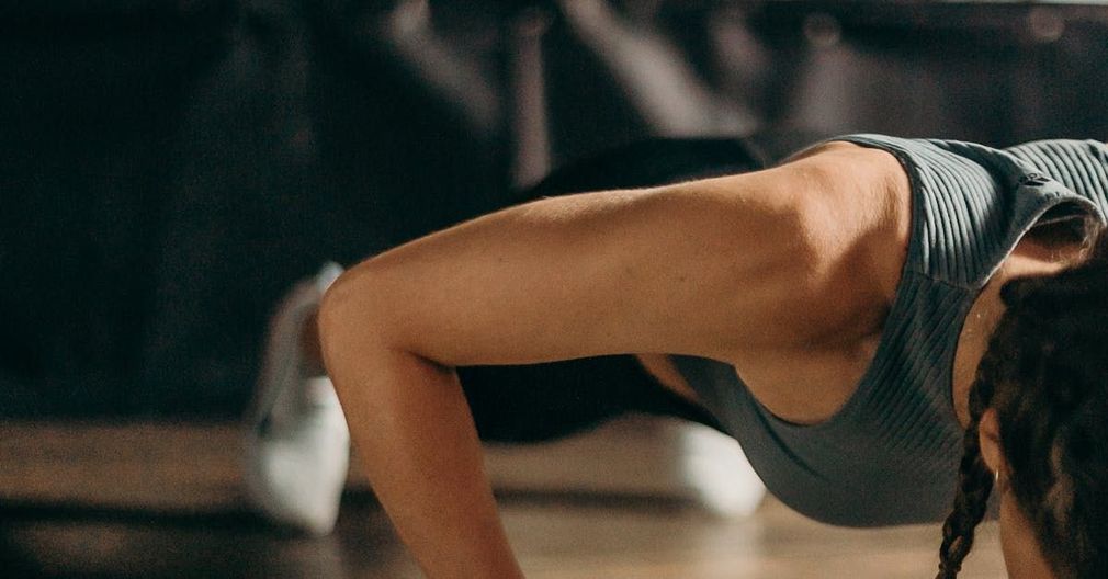 Woman in gym doing plank to strengthen core muscles during an exercise physiology session