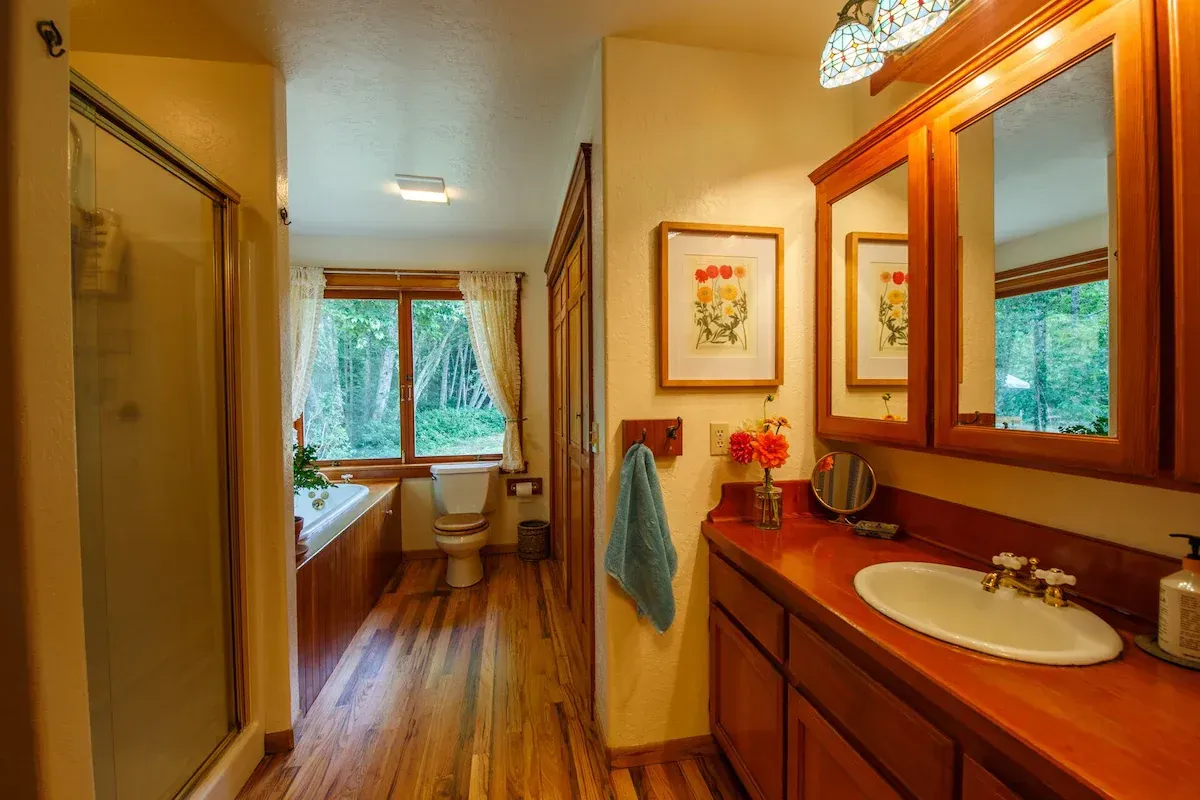 Bathroom with wooden cabinets, red countertop, and a shower on the left.