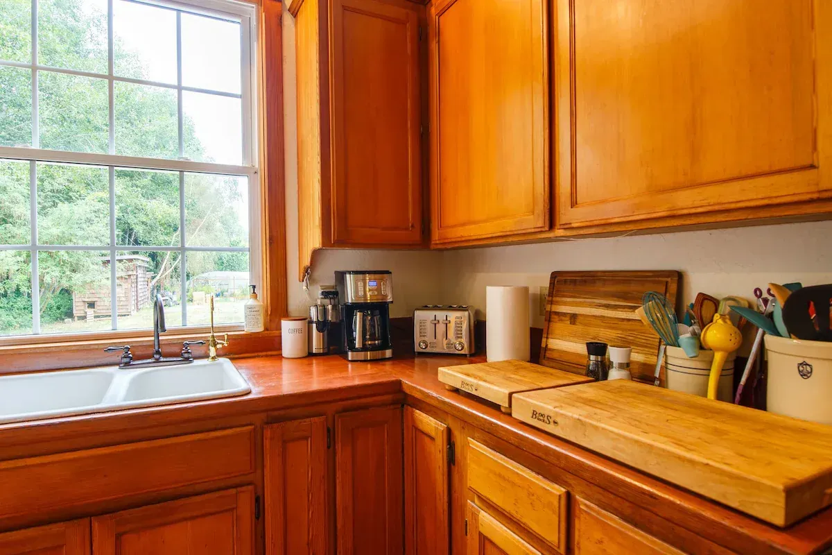 Kitchen with wood cabinets, countertop, window, and kitchenware.