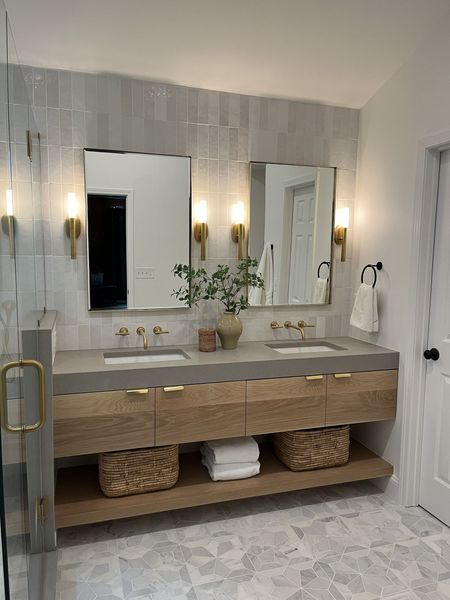 A double bathroom vanity with a concrete countertop, wood cabinet, open shelf with woven baskets, and dual wall mirrors.