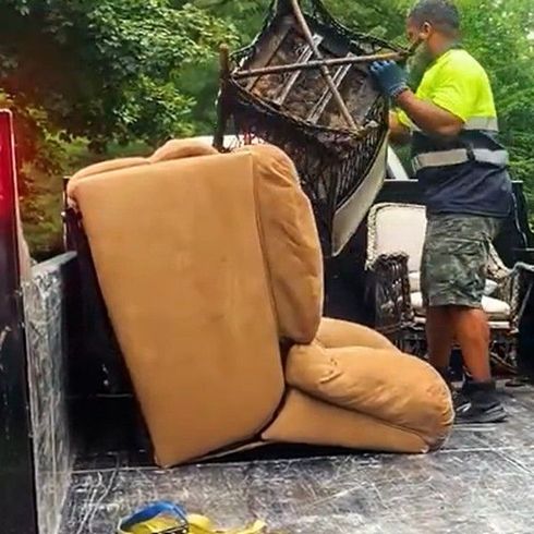 Worker hauling couch and furniture onto truck, performing couch removal services