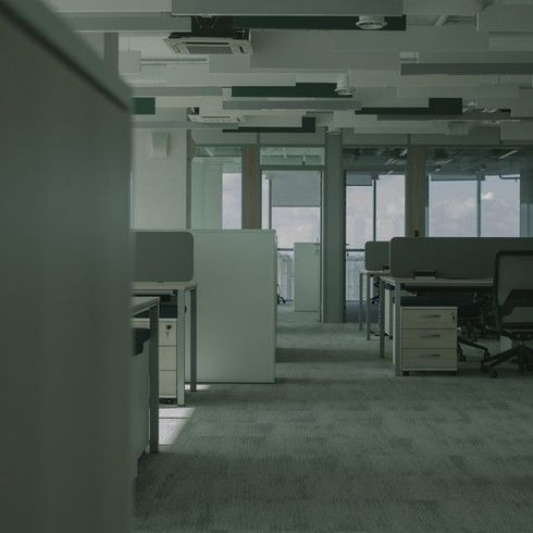 Modern open-plan office with empty cubicle desks, rolling chairs, and file cabinets ready for removal