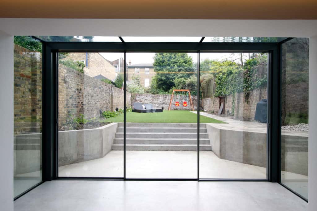 An empty room with a sliding glass door leading to a garden.