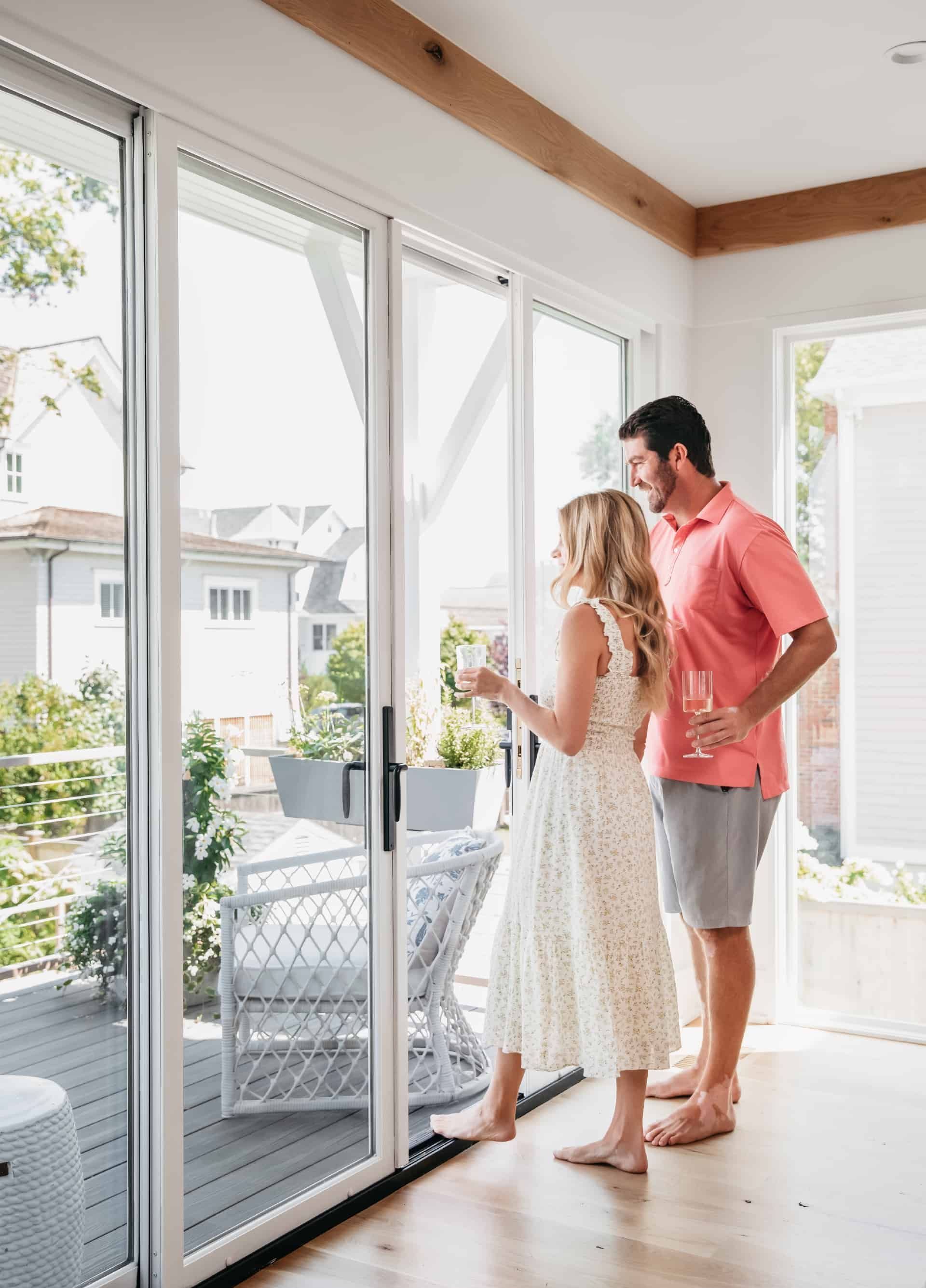 A man and a woman are standing in front of a sliding glass door.