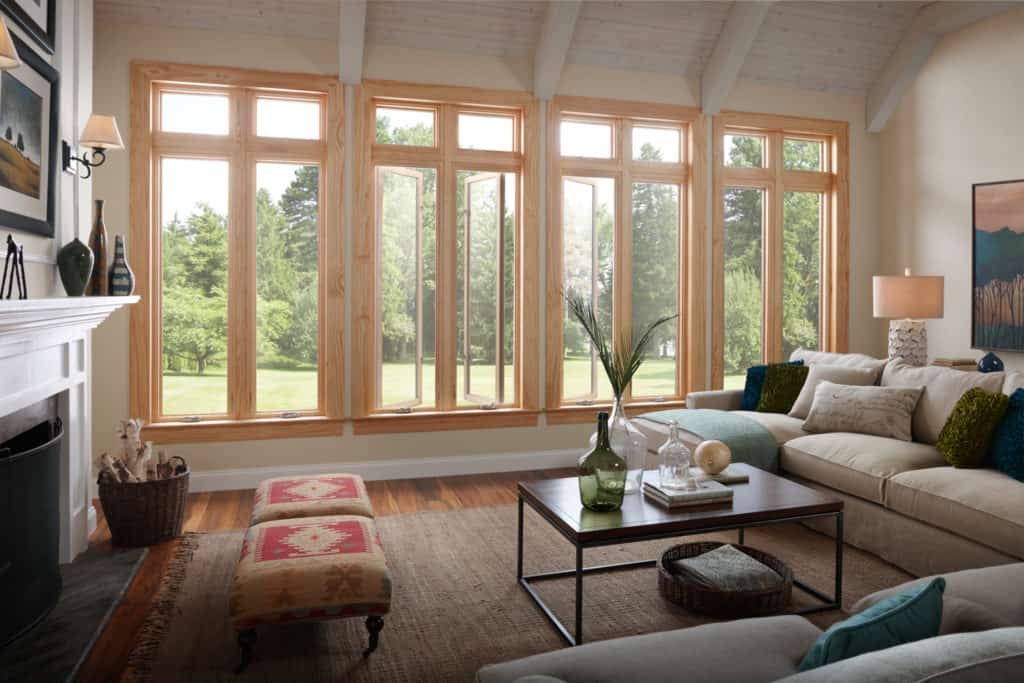 Bright living room with large windows, fireplace, sofa, coffee table, and view of a green yard