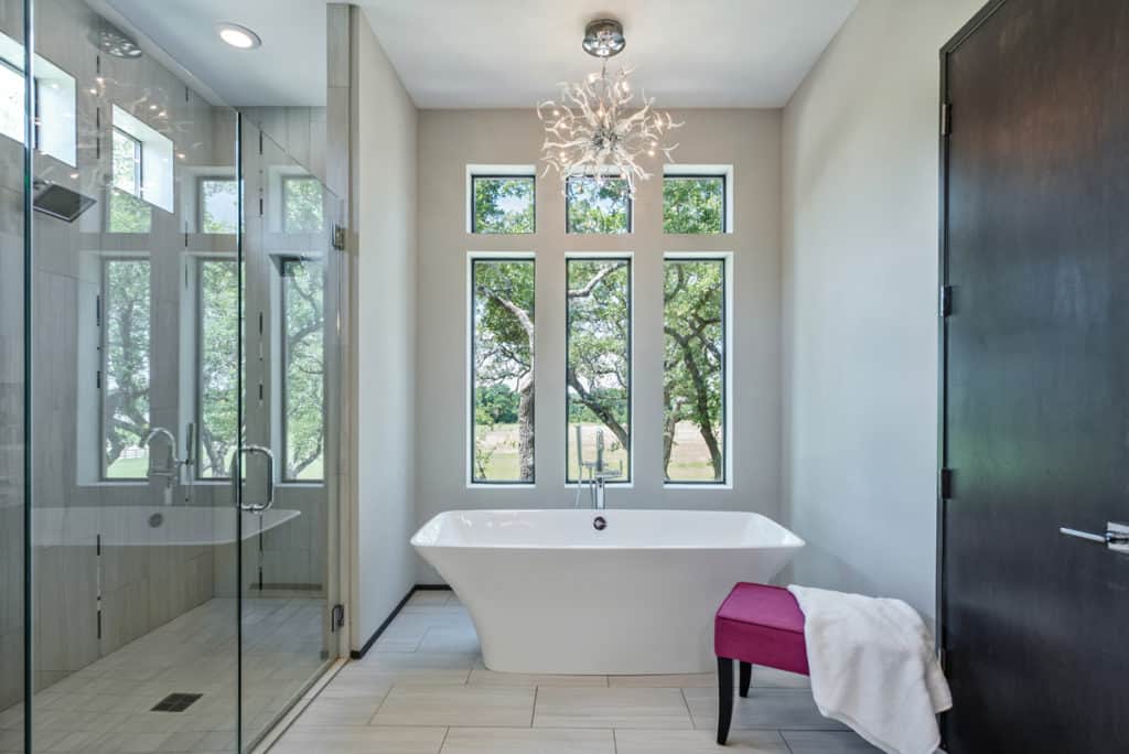Modern bathroom with freestanding tub, glass shower, and large windows