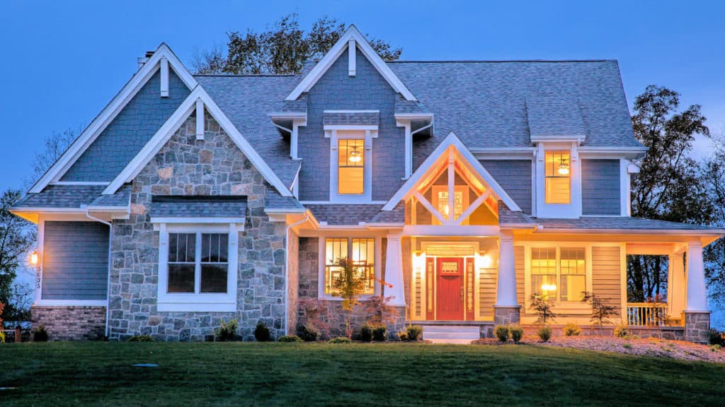 A large house with a blue roof is lit up at night