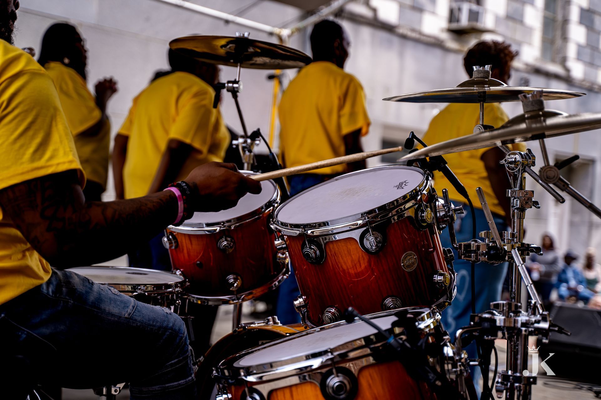 A group of people in yellow shirts are playing drums.
