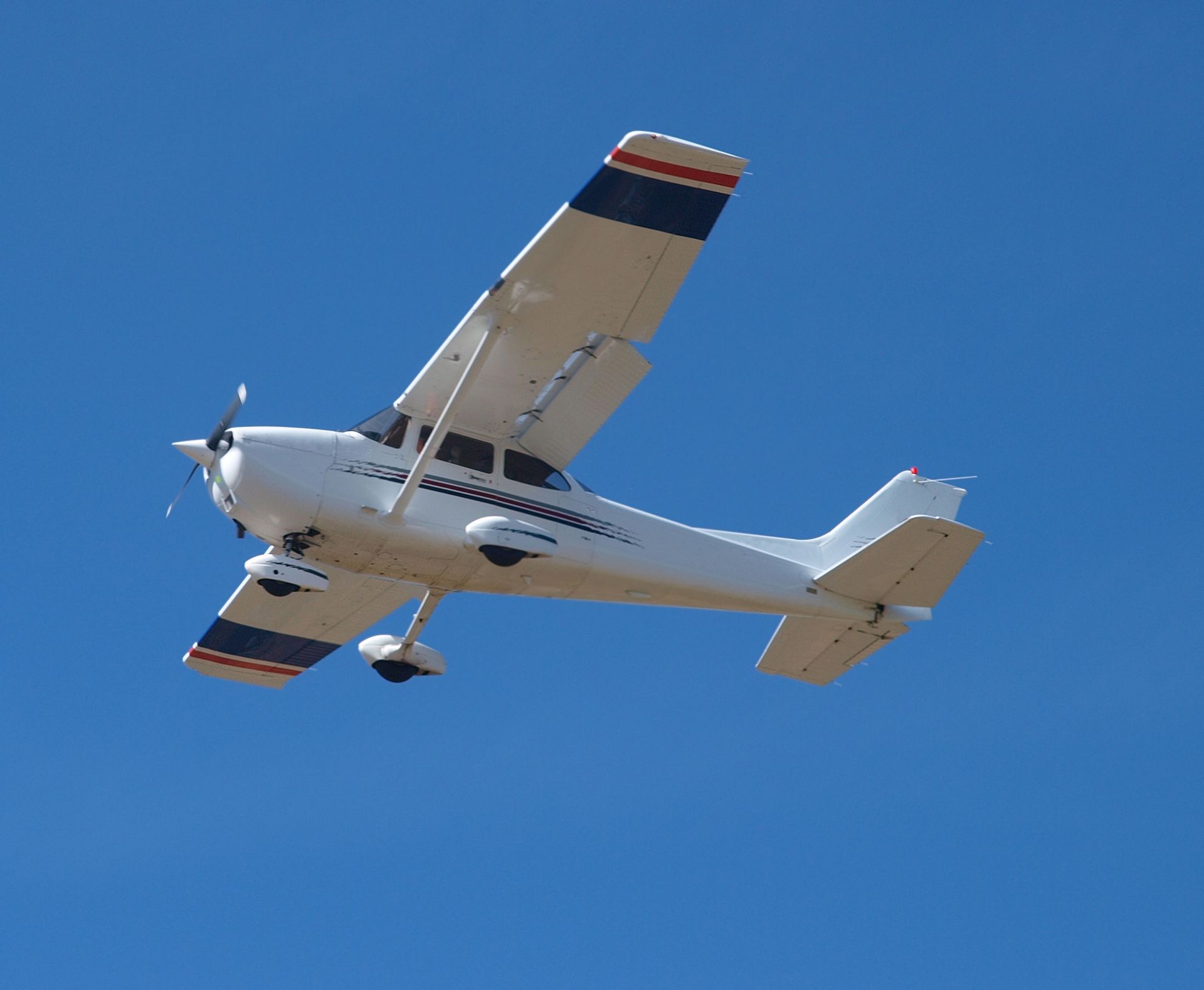 A small plane is flying through a clear blue sky