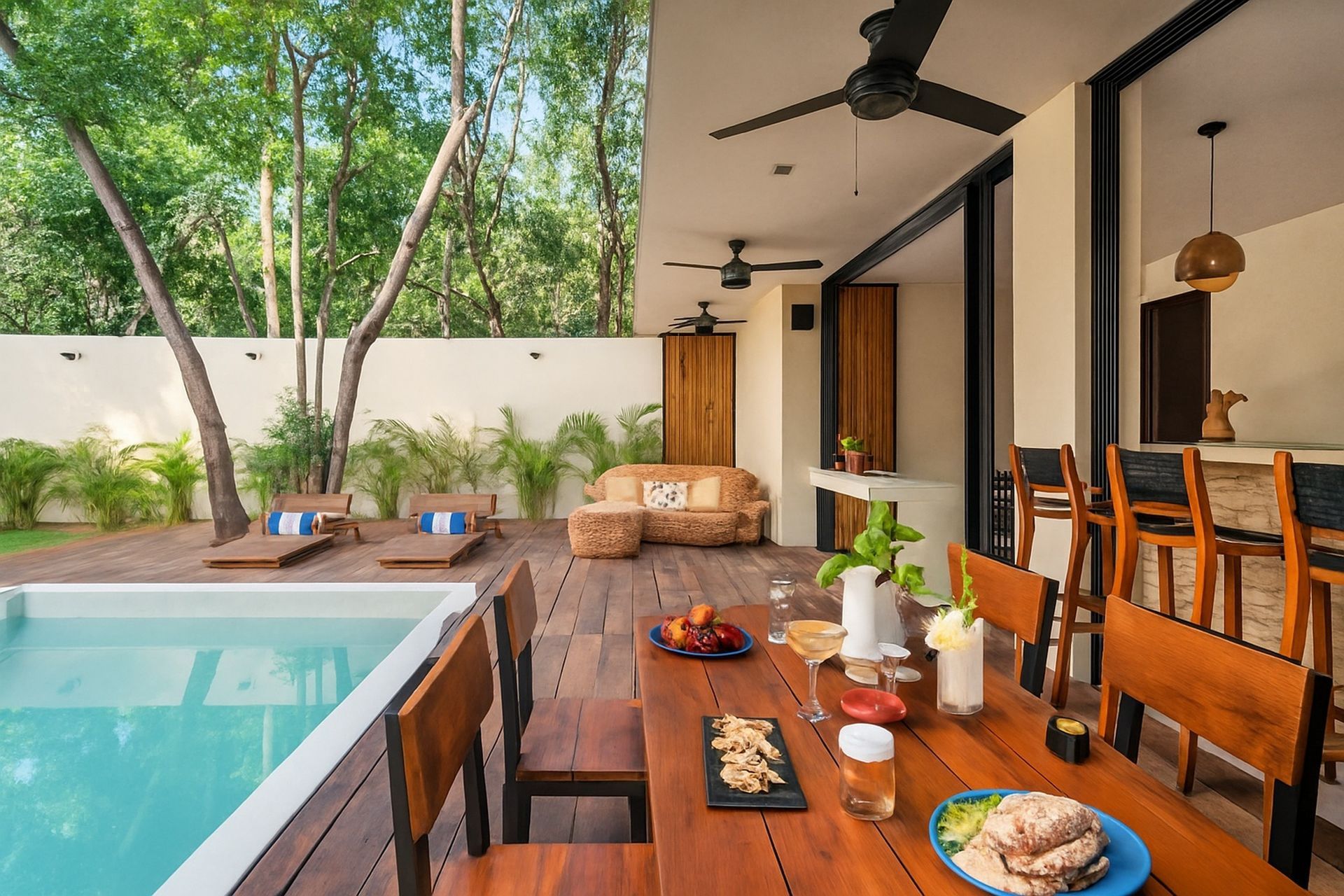 Patio with pool, wooden deck, dining table set for meal, seating area, and lush greenery.