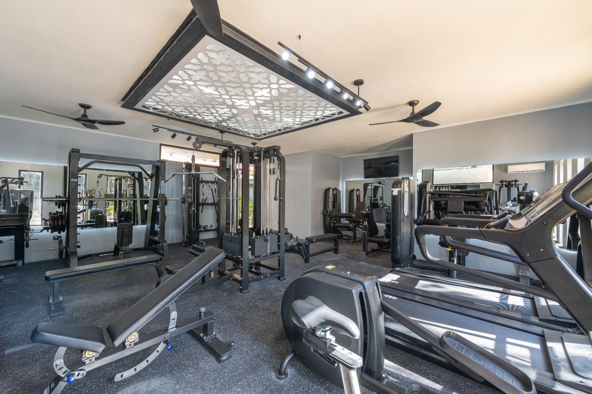 Modern gym interior with weight machines, benches, cardio equipment, and mirrored walls