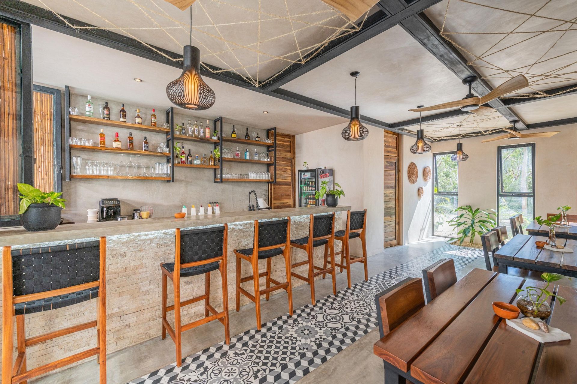 Modern bar interior with stone counter, tall stools, shelves, and patterned tile floor