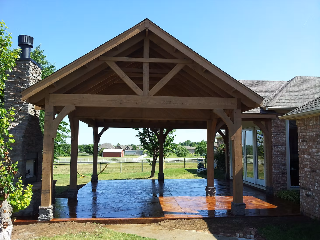 Wooden gazebo beside a pond, with brick columns and a bright blue sky in the background