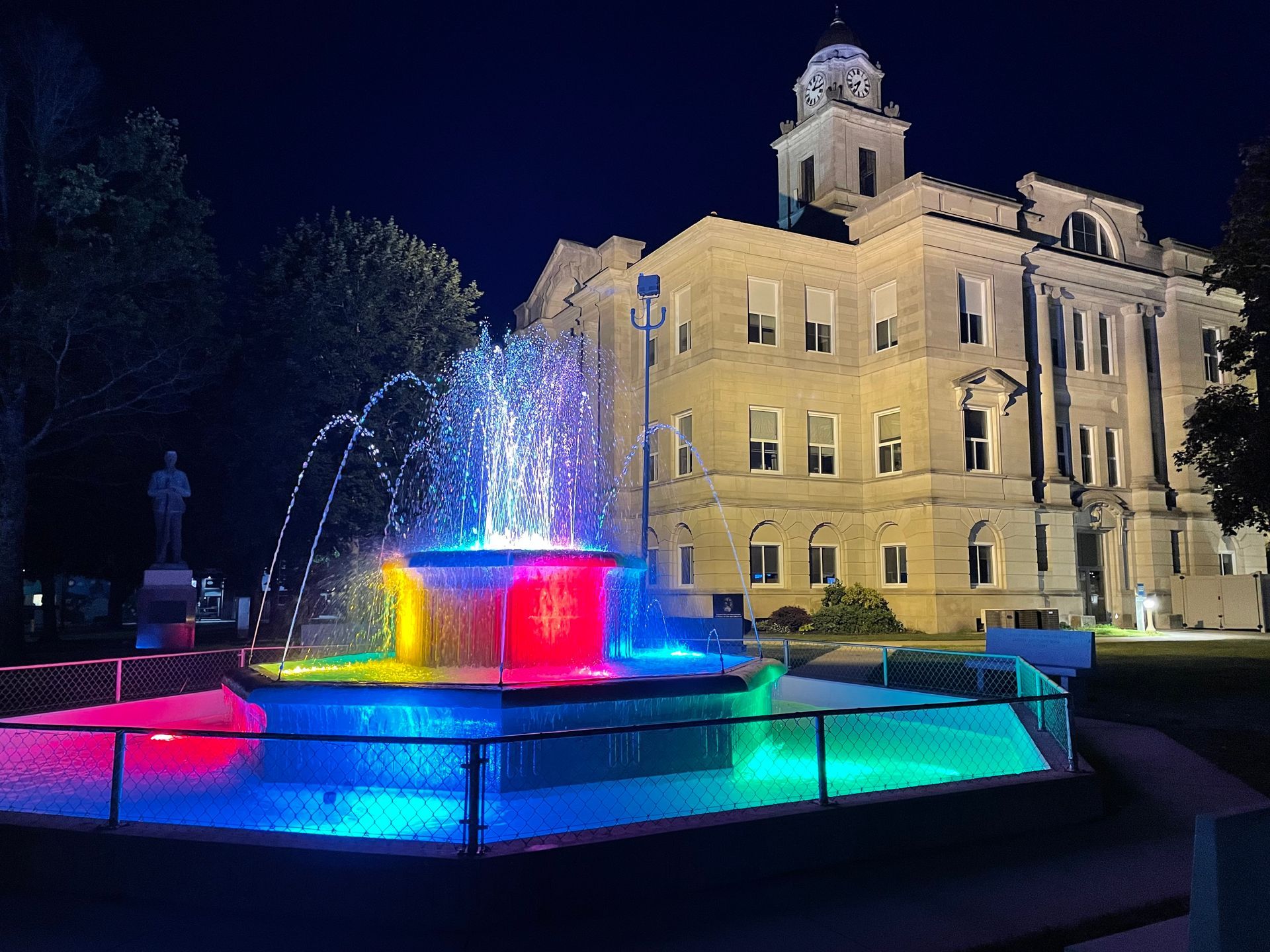 a large building with a clock tower and a fountain in front of it