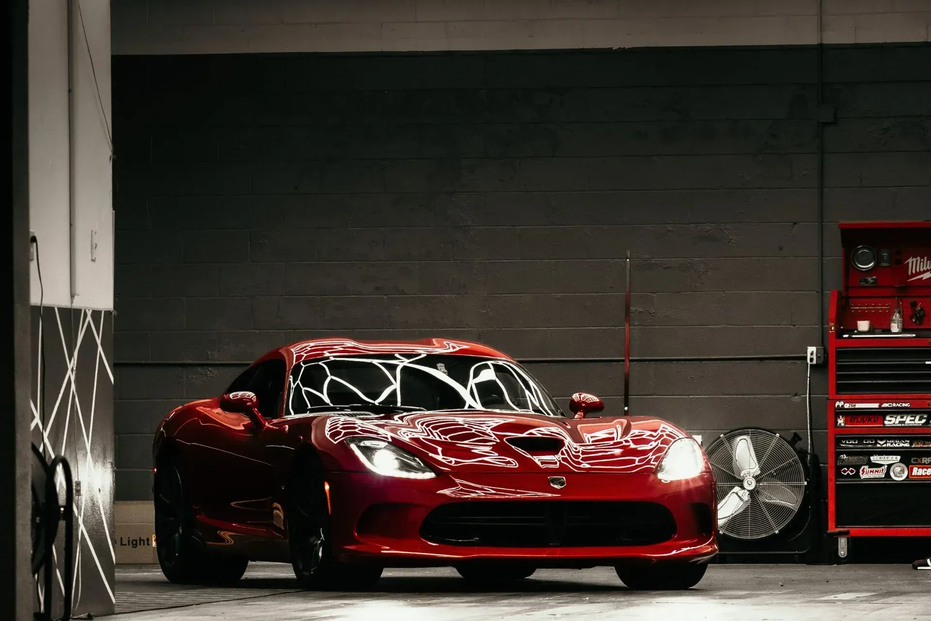 A red dodge viper is parked in a garage .