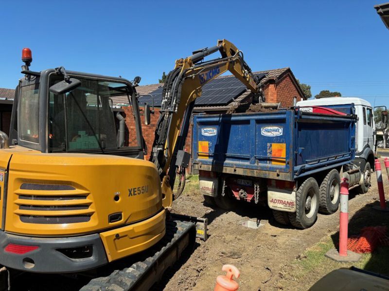 A yellow excavator is loading a dump truck on a construction site.