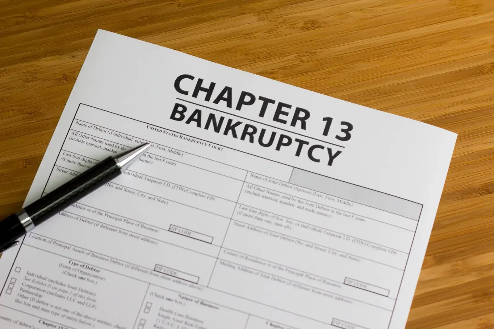A pen sitting on a chapter 13 bankruptcy form.