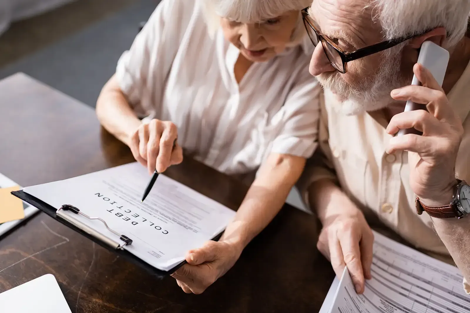 A man and a woman are sitting at a table looking at papers, representing asset protection.