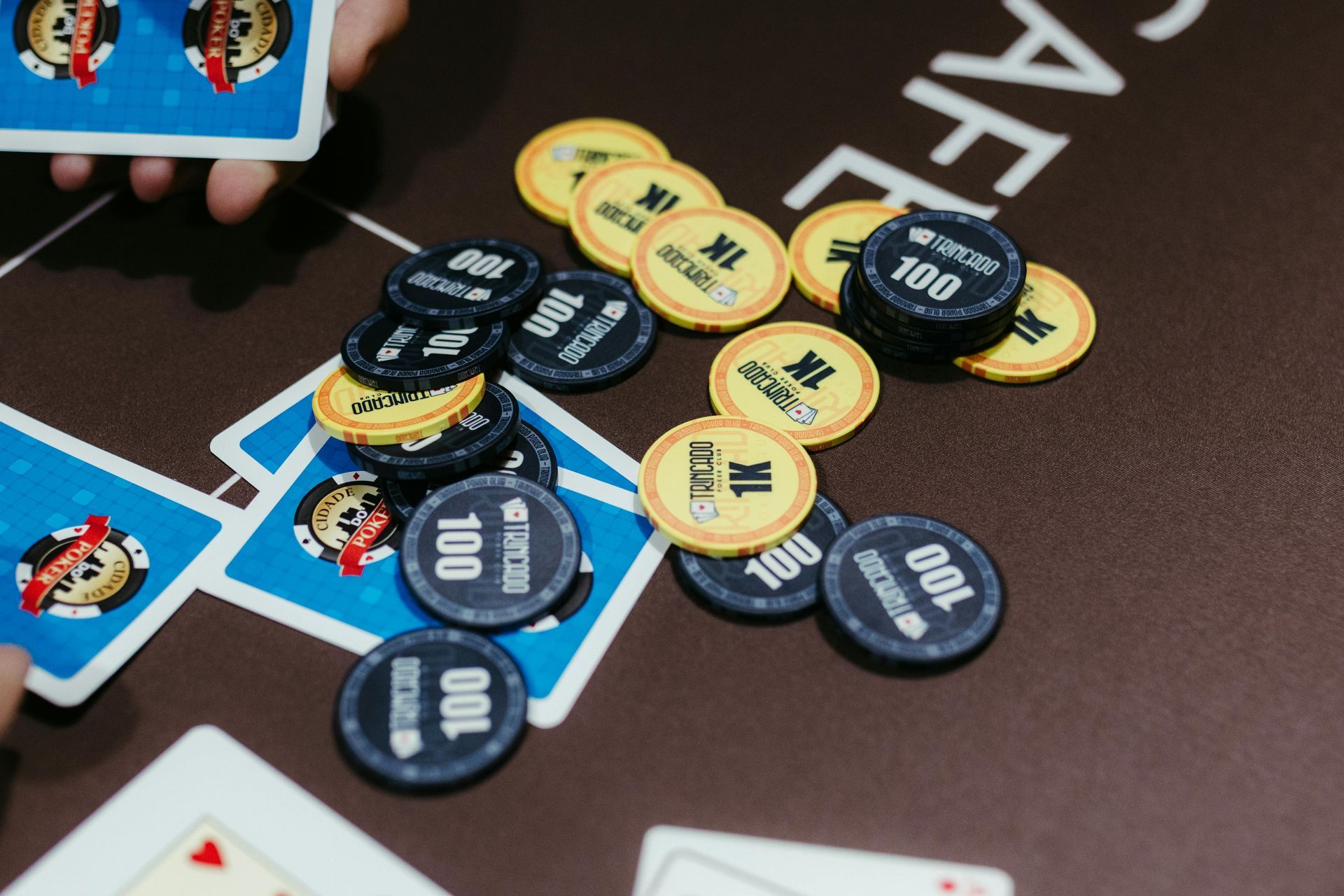 Poker chips and cards scattered on a casino table, with blue and yellow chips piled in the center