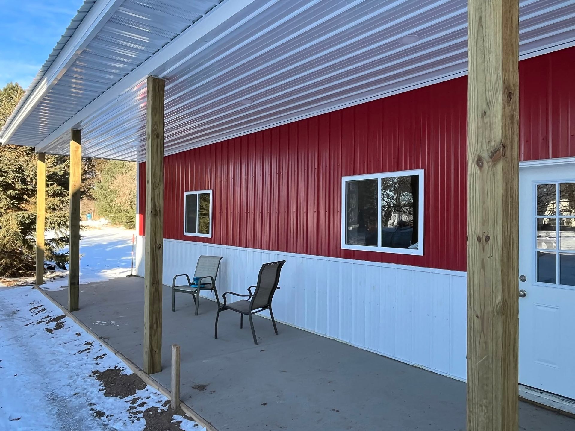 Red-and-white building exterior with porch, windows, and two chairs under an overhang.