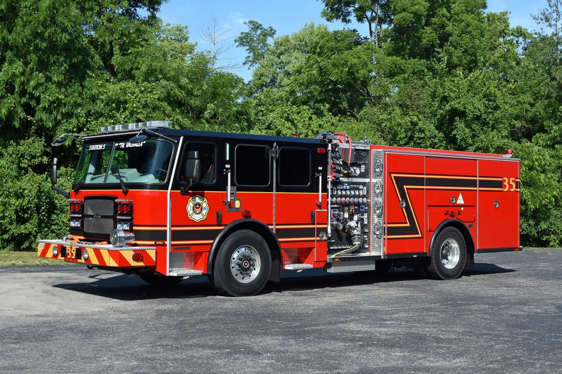 Red and black fire truck parked outdoors near trees.