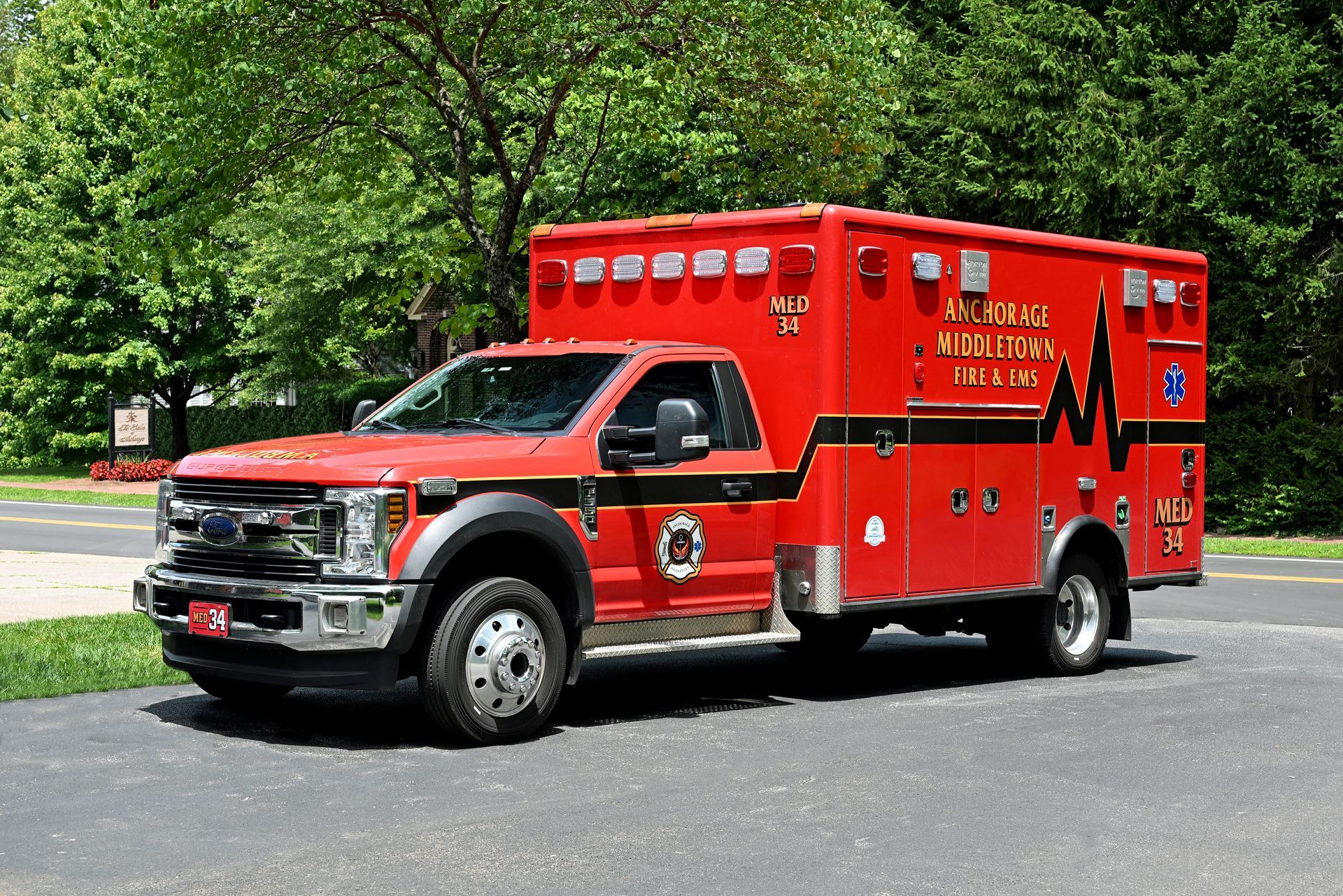 Red ambulance parked outdoors, black detailing, and emergency markings.